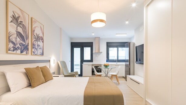 Une chambre d’hôtel moderne dotée d’un grand lit, d’un coin repas et d’une kitchenette.