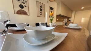 A dining table set with white bowls and plates, a vase with flowers, and a candle. - Top Moderne Wohnung im Stadtkern von Oettingen (Oettingen in Bayern)