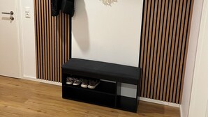 A room with a wooden slat wall, a black bench with shoe storage, and a macrame wall hanging. - Top Moderne Wohnung im Stadtkern von Oettingen (Oettingen in Bayern)