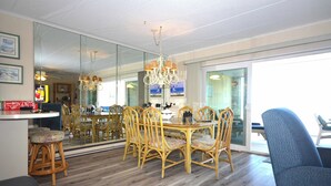 Un espace repas avec une table ronde et des chaises, un lustre et une vue à travers un mur de verre.