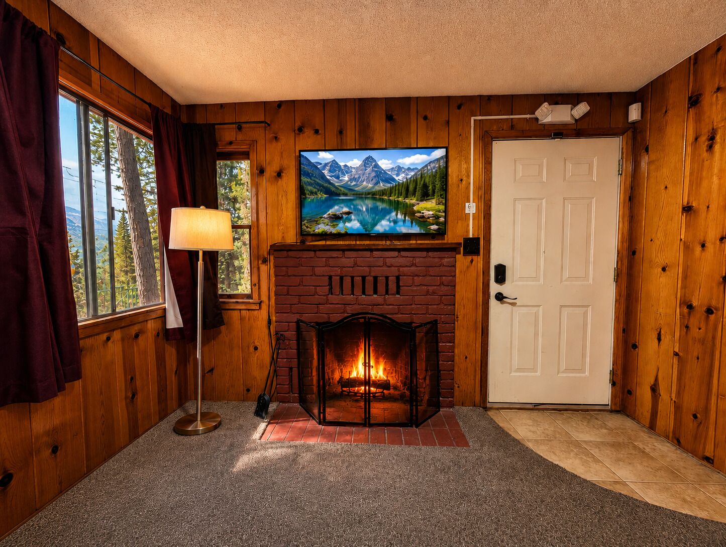 A room with wooden walls, a fireplace, a television mounted above it, and a door to the right.