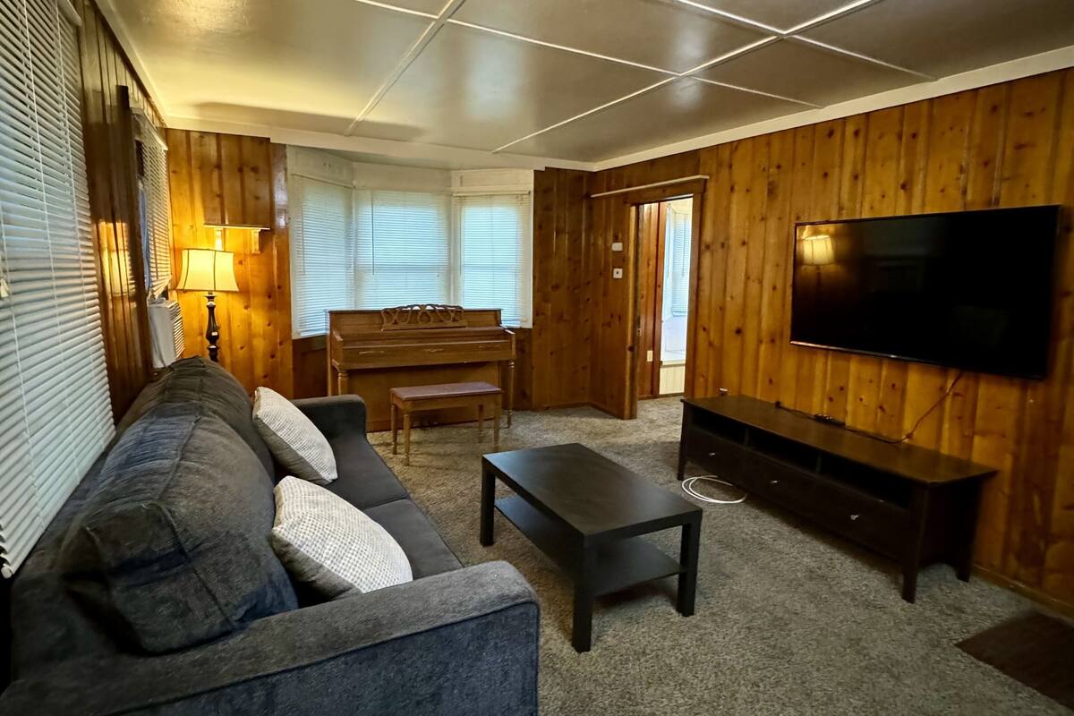 Un salon avec un canapé, une table basse, un téléviseur et un piano.