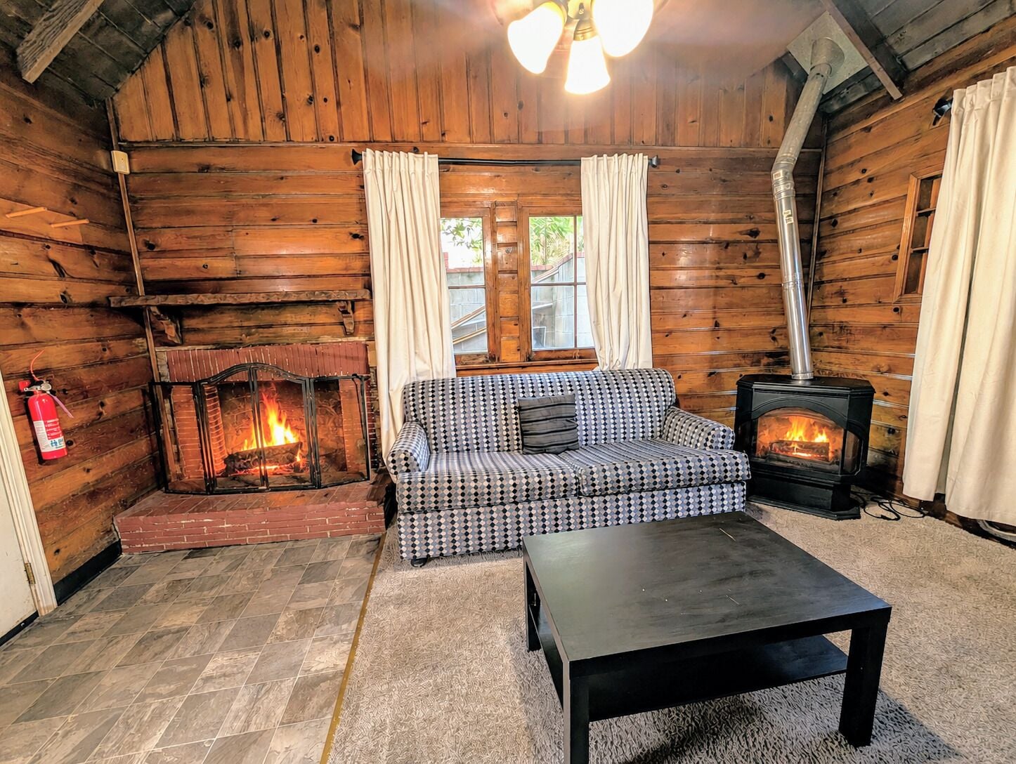 A cozy log cabin interior with a fireplace, a sofa, and a table.
