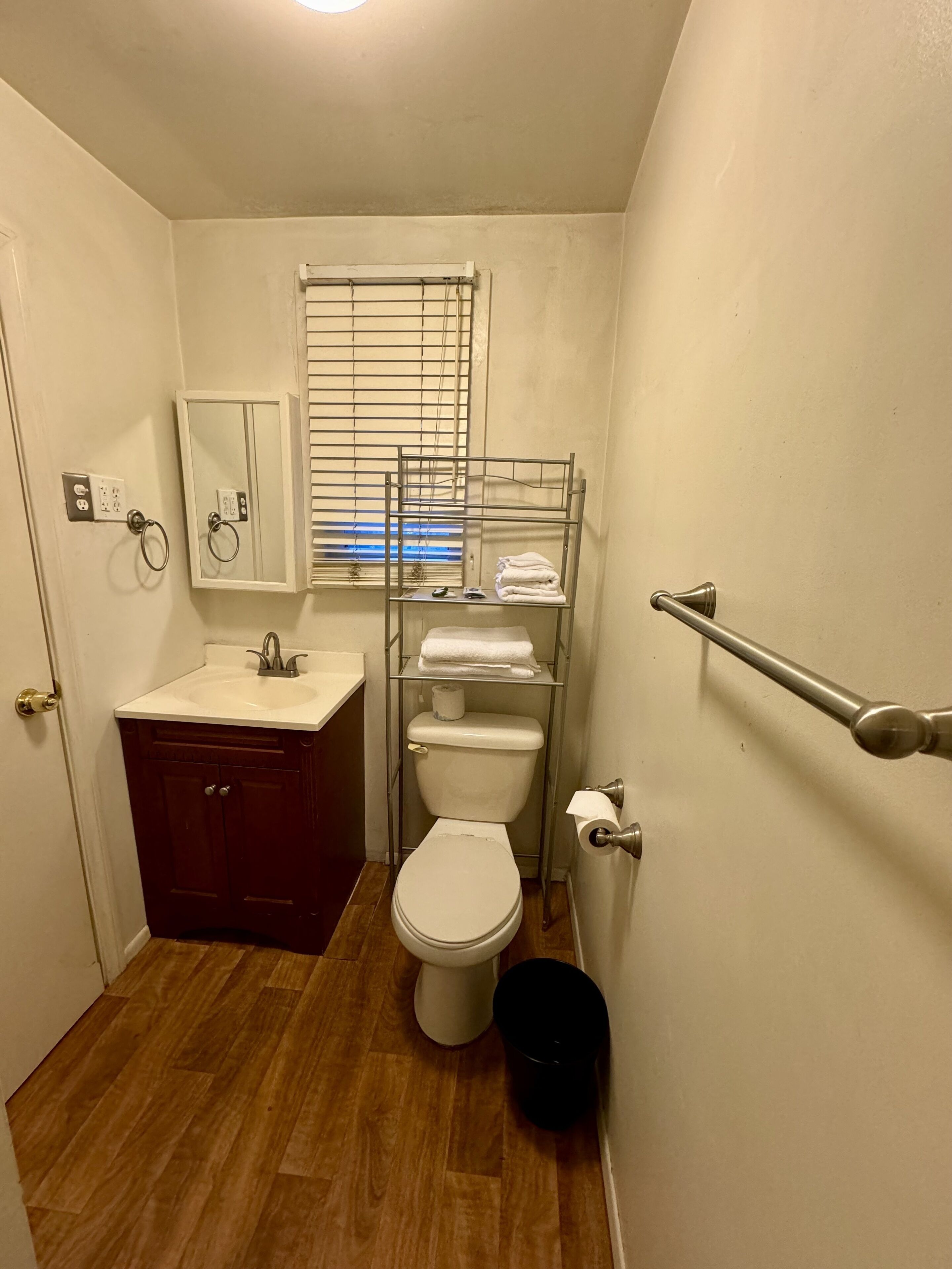 A compact bathroom with a toilet, sink, and a towel rack.