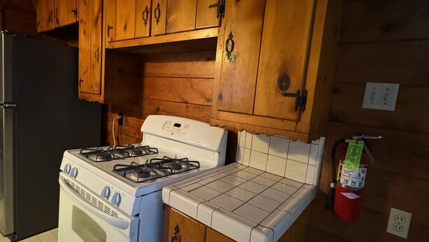 Una cocina con armarios de madera, una estufa a gas y un horno blanco.