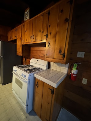 A kitchen with wooden cabinets, a gas stove, and a white oven. - Crest Lodge Historic Mountain Inn (Crestline)