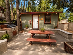 A small, single-story cabin with a barbecue grill, a wooden picnic table, and potted plants. - Crest Lodge Historic Mountain Inn (Crestline)