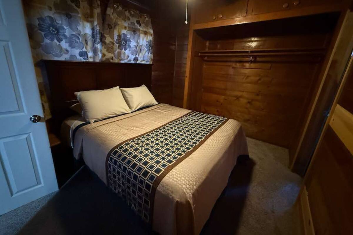 Une chambre à coucher avec un lit, une tête de lit en bois et une porte.