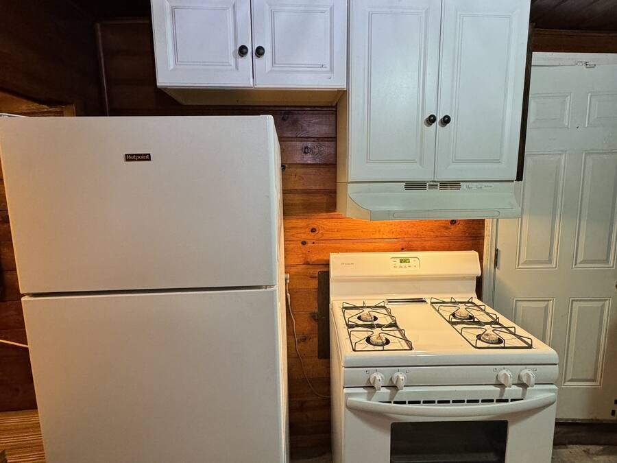 Eine Küche mit einem weißen Kühlschrank, Herd und Schränken.