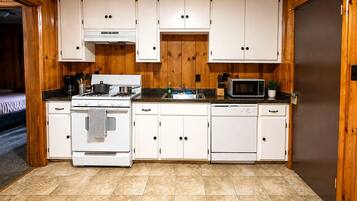 A compact kitchen with white cabinets, a stove, a microwave, and a dishwasher.
