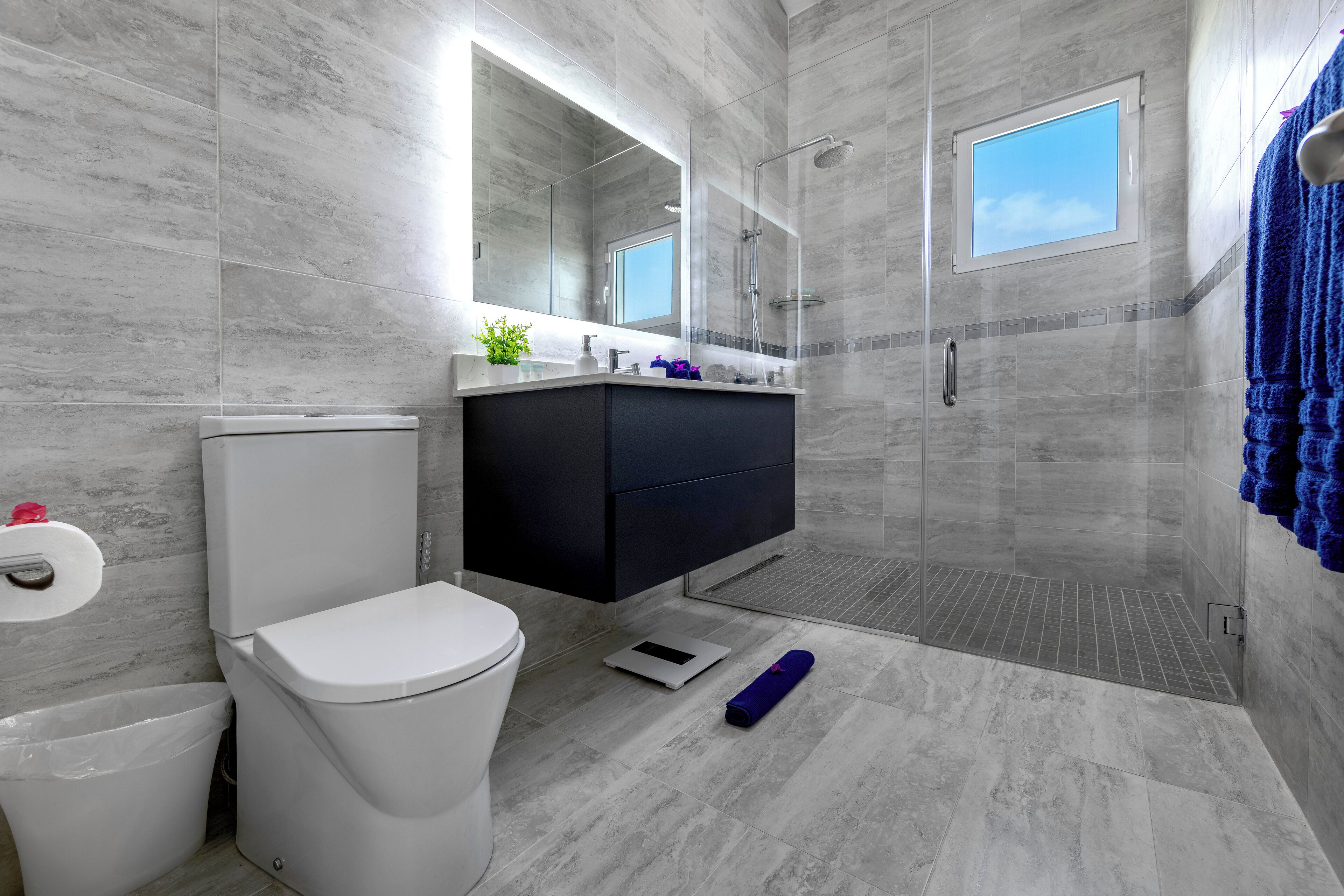 Un baño moderno con inodoro, tocador, ducha y ventana.