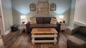 A living room with a brown sofa, two side tables with lamps, a wooden coffee table, and decorative wall sconces. - Pickwick Getaway in the Groves 7th NT Free!
(Counce)