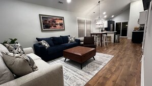 A modern living room with a sofa, ottoman, and a rug. - Quiet 2 Bedroom home near the Beach! (Sunset Beach)