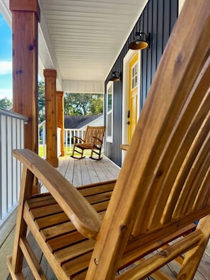 A wooden rocking chair on a porch with a view of a house and trees. - Quiet 2 Bedroom home near the Beach! (Sunset Beach)