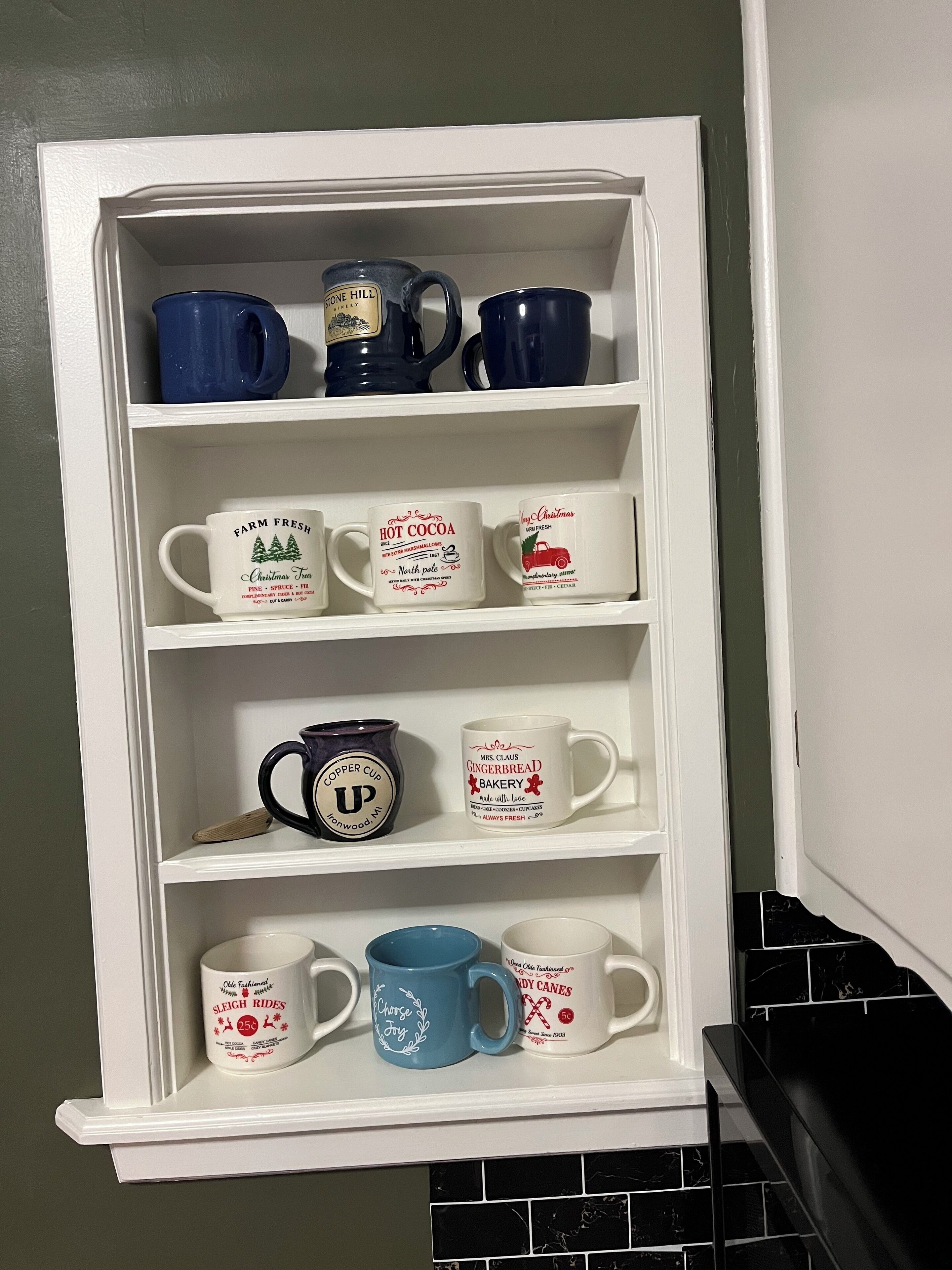 A white shelf with various mugs, each with different designs and text.