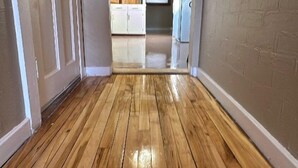 A hallway with wooden flooring leading to a kitchen area with cabinets and a refrigerator. - Cozy Corner Home Dogs Welcome (Ironwood)