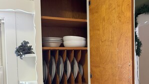 A kitchen with a white stove, a wooden cabinet with dishes, and a knife block. - Cozy Corner Home Dogs Welcome (Ironwood)