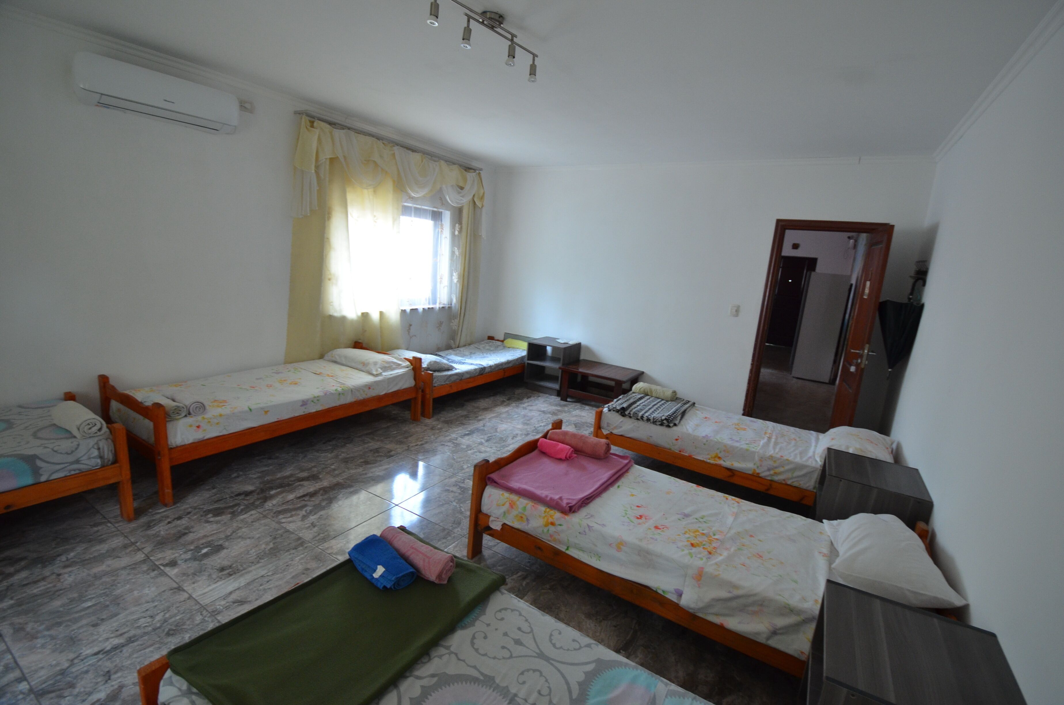 A room with three wooden beds, a small table, and a mirror.
