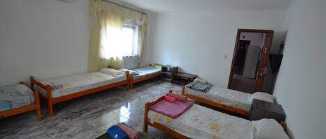 A room with three wooden beds, a small table, and a mirror.