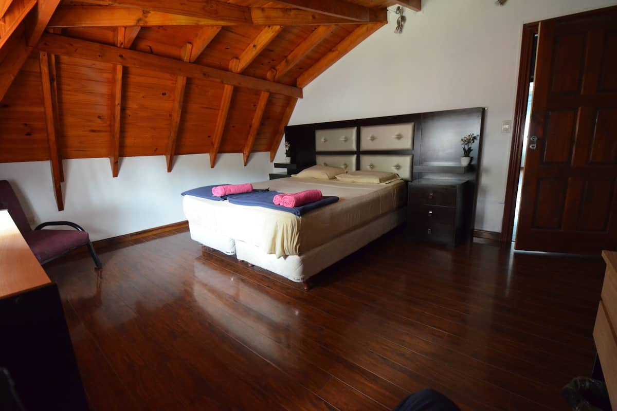 Ein Schlafzimmer mit Holzboden, einem Bett mit Kopfteil, einem Nachttisch und einer Tür.