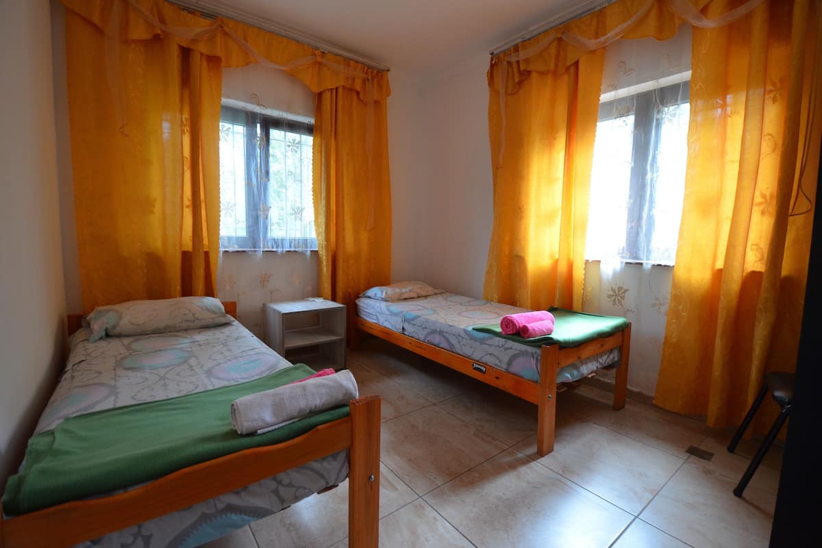 Ein Zimmer mit zwei Einzelbetten, einem kleinen Tisch und einem Stuhl.