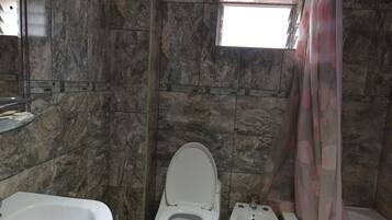 Un baño con piso de mármol, una bañera, un inodoro y un bidé.