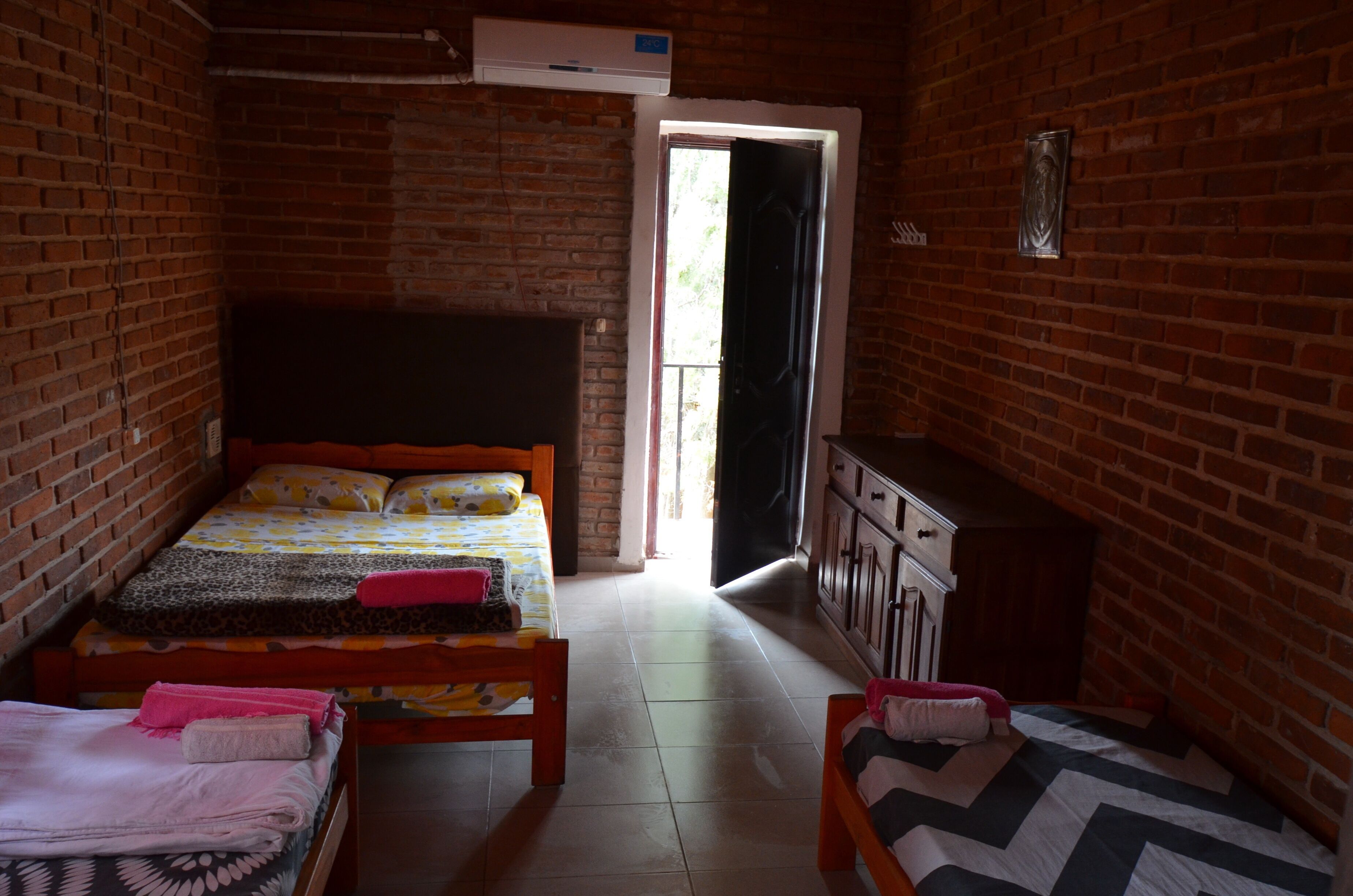 Una habitación con dos camas, un armario y una puerta que da al exterior.