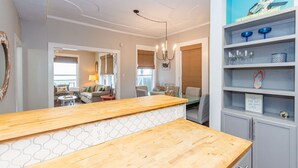 Une cuisine moderne avec un plan de travail en bois, un lustre et une étagère bleue où sont exposés des objets en verre.