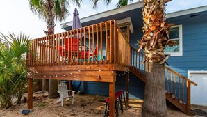 Eine Holzterrasse mit Geländer, einem roten Stuhl und einem Tisch.