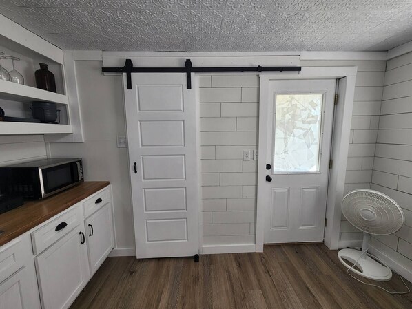 A kitchen with white cabinets, a microwave, and a sliding door.