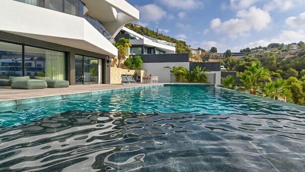 Uma casa moderna com piscina, móveis de exterior e vista para a paisagem circundante.