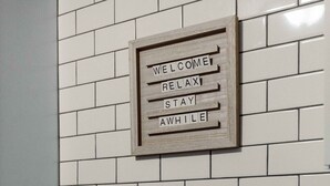 A kitchen with white subway tiles, a black faucet, and a sign that reads "WELCOME RELAX STAY AWhile". - Westlake Elegance Unit 3 (Westlake)