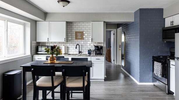 A modern kitchen with white cabinets, a black countertop, and a central island with two chairs. - Westlake Elegance Unit 3 (Westlake)