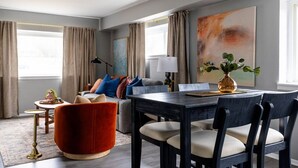 A modern living room with a dark wooden dining table, comfortable seating, and a large abstract painting on the wall. - Westlake Elegance Unit 3 (Westlake)