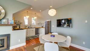 Una cocina moderna con armarios blancos, una estufa integrada y un comedor con una mesa redonda y sillas blancas.