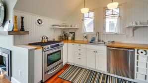 Una cocina con armarios blancos, electrodomésticos de acero inoxidable y encimera de madera.
