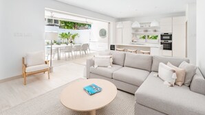 Een moderne woonkamer met een bank, salontafel en een eethoek met stoelen.