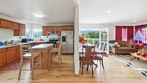 Una cocina moderna con armarios de madera, una isla central y un comedor con sillas de madera.