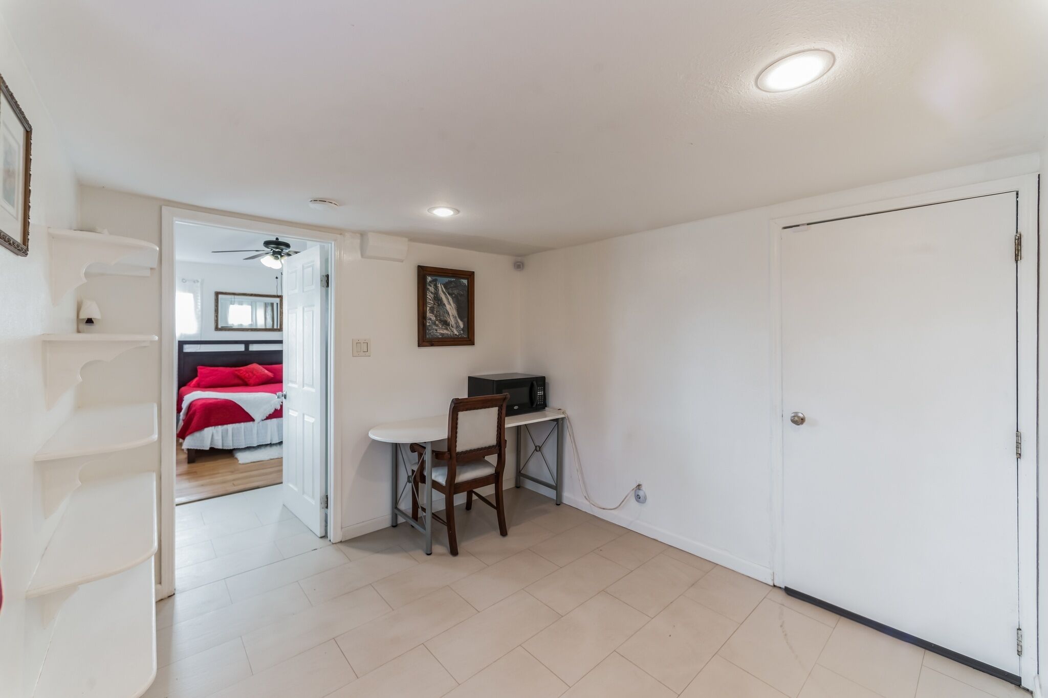 Una habitación con una cama, un escritorio con una silla, una puerta blanca y un ventilador de techo.