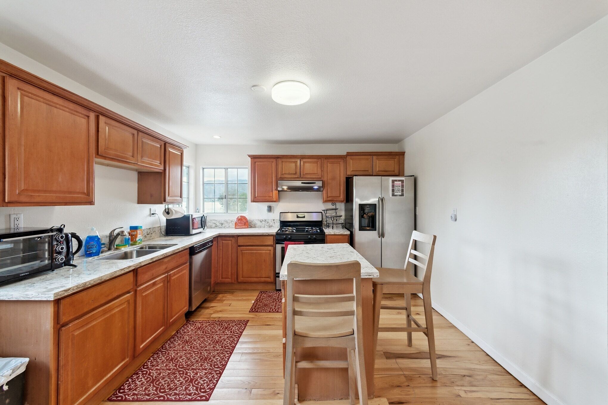 A kitchen with wooden cabinets, a stove, a refrigerator, and a dining table with chairs.