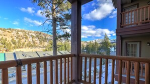 Un balcon doté d’une balustrade en bois, d’où l’on peut admirer un paysage enneigé et une montagne en arrière-plan.