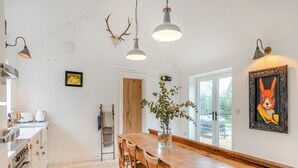 Una cocina con una mesa de madera, sillas y una lámpara colgante.
