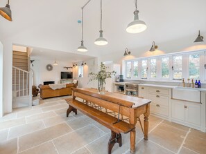 A spacious kitchen with a wooden bench, white cabinets, and pendant lighting. - 2 bedroom accommodation in Howell, near Sleaford (Howell, near Sleaford)