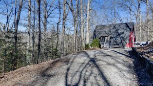 A gravel driveway leading to a house with a dark roof, surrounded by leafless trees. - Charming Franklin Cabin with Deck: Stunning Views! (Franklin)