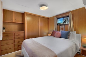 A bedroom with a bed, wooden wardrobe, and a window with curtains.