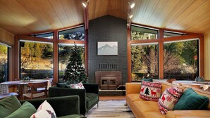 A cozy living room with a fireplace, large windows, and a Christmas tree. - Modern Cabin (Walnut) (Dunsmuir)