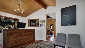 A modern living room with a wooden ceiling, a large painting, a television, and a seating area. - Modern Cabin (Walnut) (Dunsmuir)