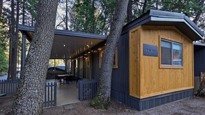 A cabin with a covered patio area, a dining table, and a sign labeled "WALNUT". - Modern Cabin (Walnut) (Dunsmuir)