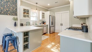 A modern kitchen with white cabinetry, a central island, and a stainless steel refrigerator. - Brenham Rental w/ Deck & Yard < 1 Mi to Downtown! (Brenham)