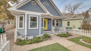 A two-story house with a grey and white exterior, a yellow front door, and a small porch with a white picket fence. - Brenham Rental w/ Deck & Yard < 1 Mi to Downtown! (Brenham)
